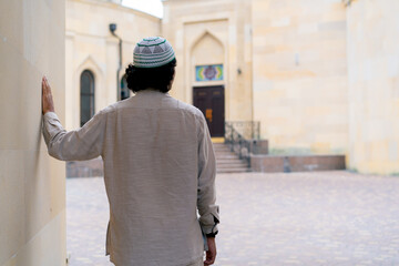 A young Arab man enters the courtyard of a Muslim mosque and looks enthusiastically at architecture