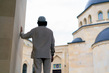 A young Arab man enters the courtyard of a Muslim mosque and looks enthusiastically at architecture