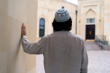 A young Arab man enters the courtyard of a Muslim mosque and looks enthusiastically at architecture