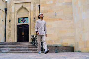 A young Arab man enters the courtyard of a Muslim mosque and looks enthusiastically at architecture