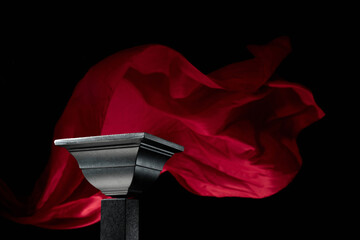 Luxury black podium on a background of waving red atlas curtain.
