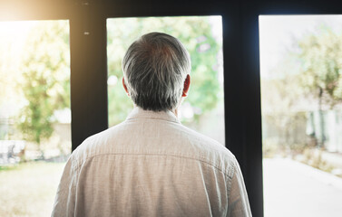 Back, mature man and thinking by window, depression and anxiety alone in home. Rear view, retirement and sad person contemplating in house, planning future and remember memory, idea or reflection
