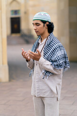 A guy of Arab appearance in national clothes with rosary around his neck prays in the courtyard of...