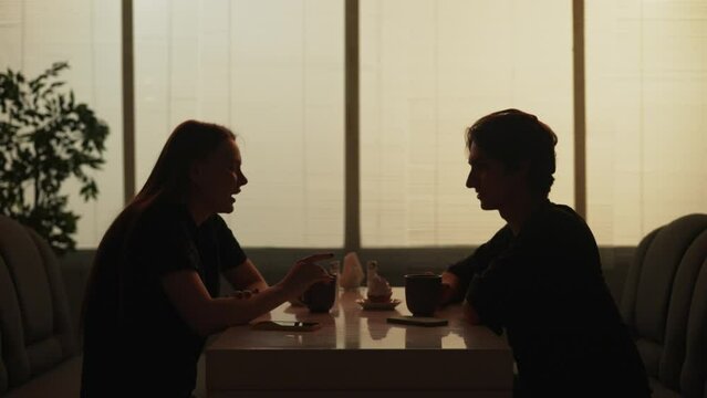 Man and woman sitting at the fast food bistro bar friendly talking, drinking coffee and eating cupcakes.