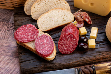 chopping board of cheeses and salami cold cuts of various varieties homemade country bread with almonds and handmade knife