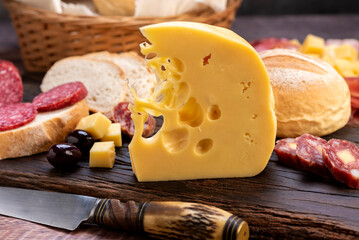 chopping board of cheeses and salami cold cuts of various varieties homemade country bread with almonds and handmade knife