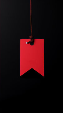 Red paper tag hanging on a rope over black background with copy space