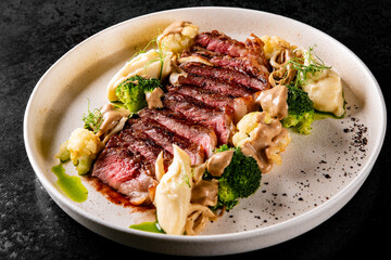 Cooked sliced beef steak rare with green broccoli.
