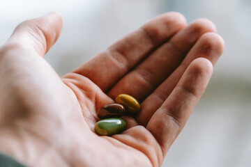 green, yellow and brown oil pills in hand,