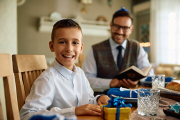 Happy Jewish kid enjoys with his father during traditional festival of lights at home.
