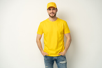 Delivery man in yellow uniform isolated on white background. Professional smiling confident male employee in cap, t-shirt courier dealer