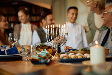 Lit menorah with Jewish extended family in background on Hanukkah.