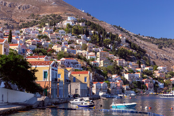 Colorful traditional multi-colored houses on the shore of the bay on Symi island.