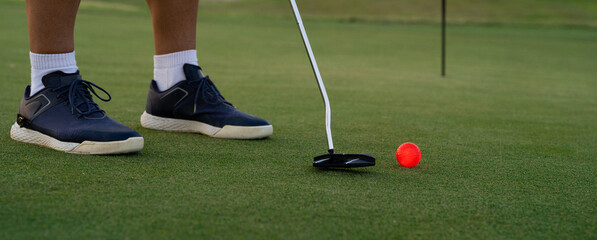 Kicking a luminous red ball on the green of a golf course. Copy space on the right - Powered by Adobe