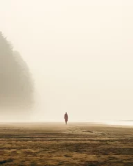 Rolgordijnen isolated person walking alone in the beach covered by dense mist © Quintes