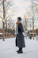 young European woman in winter clothes is skating, lady with red hair is wearing white skates on a snow rink in park. happy millennial woman is having fun. winter christmas holidays