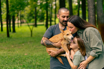 portrait of happy young family in park with dog dad mom daughter resting concept of trust care and family values