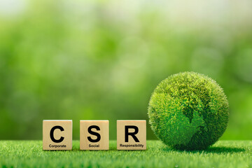 CSR (coporate social responsibility). words CSR on a woodblock and green world on a green...