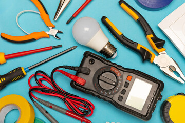 Electrician tools on background.Multimeter,construction tape,electrical tape, screwdrivers,pliers,an automatic insulation stripper, socket and LED lamp.Flatley.electrician concept.