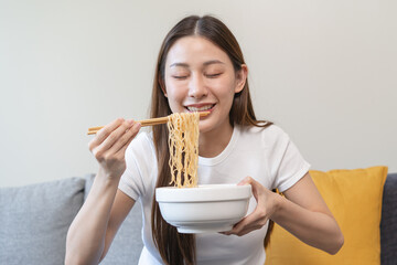 young woman eating instant noodles at home.