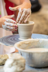 children's hands making a cup from clay