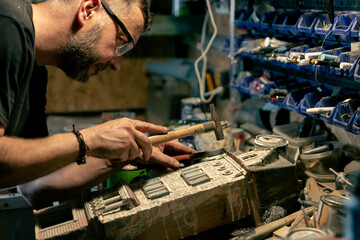 Modeller man working at scale model of miniature building in his workshop full of tools