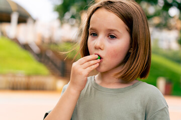 portrait beautiful cute girl eating small candies in the city park happy carefree childhood