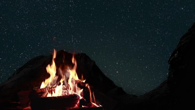  bonfire burns at night against the background of mountains and sea with bright stars