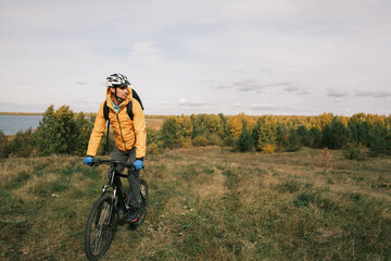  active lifestyle.A cyclist in a protective helmet with a backpack rides a mountain bike through the autumn forest.Mountain Bike