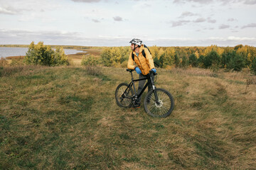Obraz premium active lifestyle.A cyclist in a protective helmet with a backpack stands with a mountain bike in the autumn forest.Mountain Bike