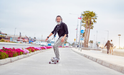 mature man white beard skateboarding on bikeway and having fun