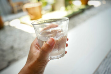 a woman holding a glass of cold water in a sunny day