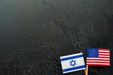 USA Israel flags. Two small American and Israeli flags lie on black old texture background opposite each other conveys partnership between two states through main symbols of these countries. Mock up. - obrazy, fototapety, plakaty