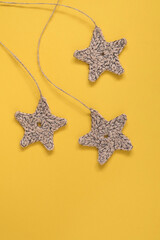 Three crochet stars on a yellow background. Copy space. Eco friendly decoration.