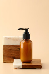 Pump amber glass cosmetic bottle on stone and wood pedestal. Beauty product design, branding.