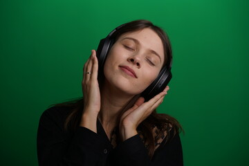 Woman listening music with headphones, shot on green background - 660046407
