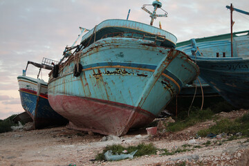 wrecked boats ships shipwreck on shore leaning against one another, close up