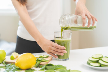 Detox juice concept, Hand of woman, girl holding bottle making green vegetable smoothie pouring in glass for diet at home kitchen, drinking healthy meal food for weight loss. Lifestyle vegan nutrition - obrazy, fototapety, plakaty