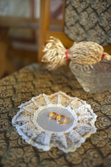 On the chair is a tray with golden wedding rings on holy water for consecration.