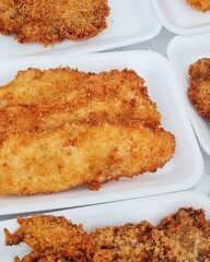 Breaded white hake fillet (Cynoscion leiarchus) in Styrofoam packaging for sale.