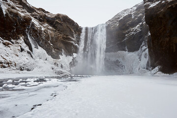 Breathtaking winter scene in Iceland with a magnificent waterfall, snow-covered landscape