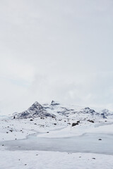 A mesmerizing Icelandic landscape showcasing a blue lagoon, vast frozen lake, snow-covered mountains