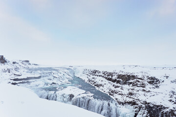 Fototapeta na wymiar Stunning snow-covered waterfall in Iceland, captured with grandeur, sunlight adding a soft glow to the serene beauty