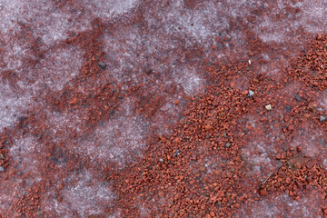 Mesmerizing red volcanic landscape with textured ground, scattered rocks, and a distant layer of snow contrasting the warm red.