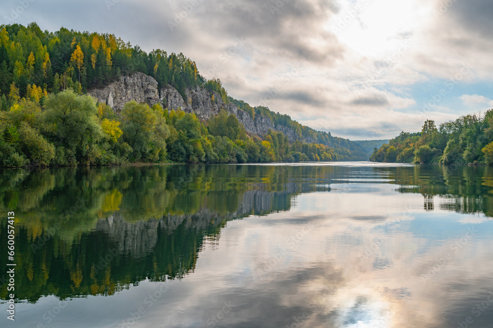 Wall mural autumn landscape, view of the high rocky bank of the sylva river, mirror image in the water.