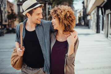 Young mixed couple embracing each other while having a stroll in the city