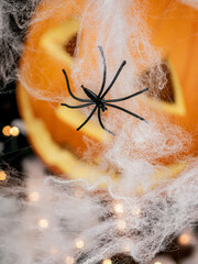 Carved pumpkin for Halloween with white spider web with black spiders, with candlelight