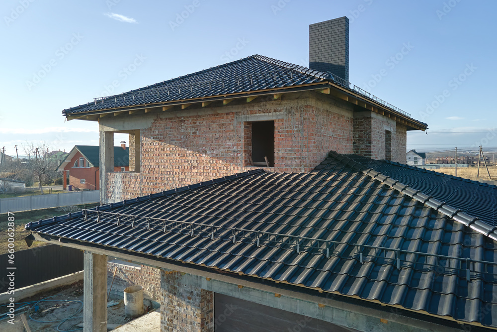 Wall mural aerial view of house roof top covered with ceramic shingles. tiled covering of building under constr