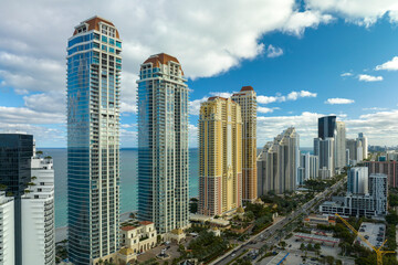 Obraz premium Aerial view of Sunny Isles Beach city with congested street traffic and luxurious highrise hotels and condos on Atlantic ocean shore. American tourism infrastructure in southern Florida