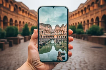 Fototapete Close up of a hand holding a mobile phone and taking a picture of Rome © michaelheim